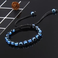 Detail van handgeweven Evil Eye-armband met blauwe kralen op zwart reflecterend vlak - Zwart (B0039)