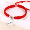 Macro detail of red woven rope bracelet featuring a heart pendant with brother engraving - Red String Brother Heart Style / Brother Silver (J1374)