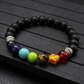 Makroansicht der 7-Chakra-Lavasteinperlen mit Tigerauge auf schwarzem Holzgrund - Schwarz Matte Stein 7 Chakra