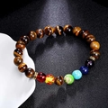 Handgemachtes Tigerauge-Armband mit sieben Chakra-Perlen auf schwarzem Lederhintergrund - Tigerauge
