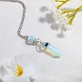 Close-up of opalite hexagonal prism pendant necklace on a white textured background - Light Blue (N0281)