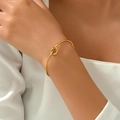 Detailed close-up of a minimalist gold knotted cuff bracelet on a female model's wrist - Stainless Steel-Gold