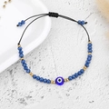 Macro shot of blue Evil Eye beaded bracelet with adjustable black braided wax cord - Gold Bead Dark Blue Eye (B2121)