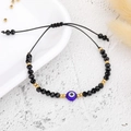 Detail of beaded bracelet with blue evil eye charm and adjustable black woven cord strap - Gold Bead Black Eye (B2124)