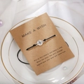 Dettaglio del bracciale con bussola su carta dei desideri con perle e decoro - Bussola (B2511)
