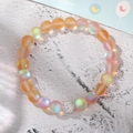 Detail of matte iridescent moonstone beads and silver crystal charm on elastic bracelet - Orange