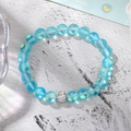 Macro detail of a beaded elastic bracelet with light blue moonstone beads and a crystal charm - Lake Blue