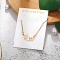 Macro view of golden Leo gothic pendant on stainless steel chain over white display card - Leo-Gold