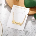 Detail of golden Gemini stainless steel gothic letter pendant on elegant white card display - Gemini-Gold
