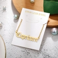 Detailed view of Capricorn gold stainless steel letter pendant necklace on wooden base - Capricorn-Gold