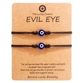 Detail of two handmade evil eye woven bracelets on a craft paper card for protection - Blue Bead Black Cord (B2937)