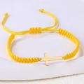 Detail eines gelben handgewebten Armbandes mit einem polierten goldenen Kreuzanhänger - Edelstahl Gold Kreuz (B3423)