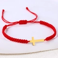 Detail eines roten geflochtenen Armbands mit poliertem goldenem Edelstahl-Kreuzanhänger - Edelstahl Gold Kreuz (B3425)