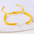 Nahaufnahme des gelben geflochtenen Armbands mit einem polierten silbernen Metallkreuz - Edelstahl Silber Kreuz (B3436)