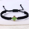 Close-up van een handgeweven zwarte armband met een kruishanger in groen kleurverloop - Hematiet Kruis (B3444)