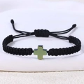 Detail eines verstellbaren schwarzen geflochtenen Armbands mit grünem Kreuzanhänger - Hämatit Kreuz (B3447)