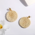 Close-up of handmade woven rattan hoop earrings with gold metal stud in boho style - Round