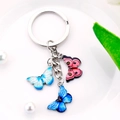 Macro detail of three-color butterfly keychain with pink and blue enamel pendants - Light Blue Dark Blue Pink Wing Style (M745)