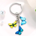 Detailed macro view of colorful enamel butterfly pendants on a silver metal keychain ring - Light Blue Dark Blue Yellow Textured Butterfly Style (M748)