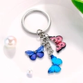 Detailed view of colorful butterfly pendants on a silver metal keychain with pearl decor - Pink Dark Blue Bright Blue Eye-spot Butterfly Style (M749)