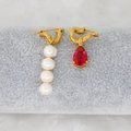 Detail of asymmetric earrings with white pearls and a red teardrop-shaped gemstone - Dark Red