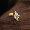 Macro shot of gold stainless steel butterfly stud earring with clear zircon inlay on wood - Marquise Petal Flower (3441) / Gold