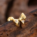 Macro shot of gold bow stud earring with zircons and ball screw back on dark bark - Double Zirconia Bow Style (3149) / Gold