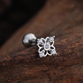 Macro shot of silver clover cartilage stud with clear zircons on a wooden background - Hollow Floral Style (3446) / Silver