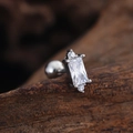Macro detail of stainless steel tragus stud with rectangular zircon on aged wood - Rectangular Gemstone Style (3451) / Silver