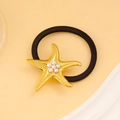 Dettaglio dell'elastico per capelli con stella marina dorata e perle bianche - Oro