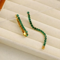 Dettaglio di orecchini a nappa dorati con strass verdi in una scatola per gioielli - Oro-Verde