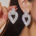 Dettaglio di lussuosi orecchini a cuore traforati con cristalli brillanti argentati - Stile Strass Completo Cuore Geometrico Cavo (BXE038S)