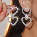 Dettaglio orecchini a doppio cuore di lusso con cristalli scintillanti sulla modella - Doppio Cuore Esagerato / Argento