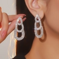 Dettaglio di orecchini a cuore di lusso con strass scintillanti indossati da una modella - Stile Strass Completo Ovale Nidificato a Tre Strati (BXE050S)