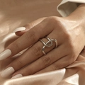 Elegante anello doppio incrociato argentato al dito su sfondo di seta pregiata - Aperto Regolabile / Stile Geometrico Audace Argento (JZ512S)