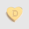 Makro-Detail eines polierten goldenen Herzanhängers mit geschnitztem Großbuchstaben D - Buchstabe D Stil / Stahlfarben