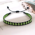 Detail of handmade woven bracelet with neon pixel art pattern and adjustable cord - Black Green Yellow Figures (KZ-0002A)