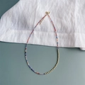 Minimalistische 2mm gekleurde zirkoon kralenketting met gouden sluiting op witte stof - Meerkleurige Kralenstijl (SJX220009A)
