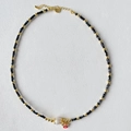 Détail du pendentif œil rouge et perle blanche sur un collier de perles dorées - Perle Cube Noire (SJX220010B)