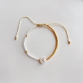 Detail van kralenarmband met witte en gouden kralen en een bedeltje met de letter N - Letter N (BLS220006N)