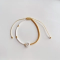 Detailopname van kralenarmband met gouden TOHO-kralen en wit bedeltje met letter O - Letter O (BLS220006O)