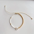 Detail van verstelbare kralenarmband met gouden letter Q bedeltje en kleine glaskralen - Letter Q (BLS220006Q)