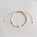 Detailopname van een handgemaakte kralenarmband met witte en gouden kralen en de letter V - Letter V (BLS220006V)