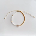 Detail van handgemaakte kralenarmband met witte en gouden TOHO-kralen en letter W bedeltje - Letter W (BLS220006W)