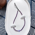 Detail view of purple beaded phone wrist strap featuring white resin cloud charms - Deep purple