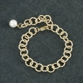 Detail van gouden schakelarmband met fijne textuur, karabijnsluiting en parelhanger - Schelp Parel Armband