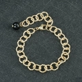 Gedetailleerd beeld van een gouden schakelarmband met een elegante zwarte kraal - Zwarte Agaat Armband