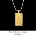 Macro detail of gold tarot card necklace featuring the engraved Fool design on black background - The Fool / Gold