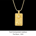 Macro shot of gold tarot card necklace with Sun and Moon engraving and inlaid stone - Moon / Gold