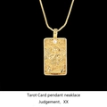 Macro shot of gold tarot pendant Judgement with sparkling cubic zirconia on black base - Judgement / Gold
